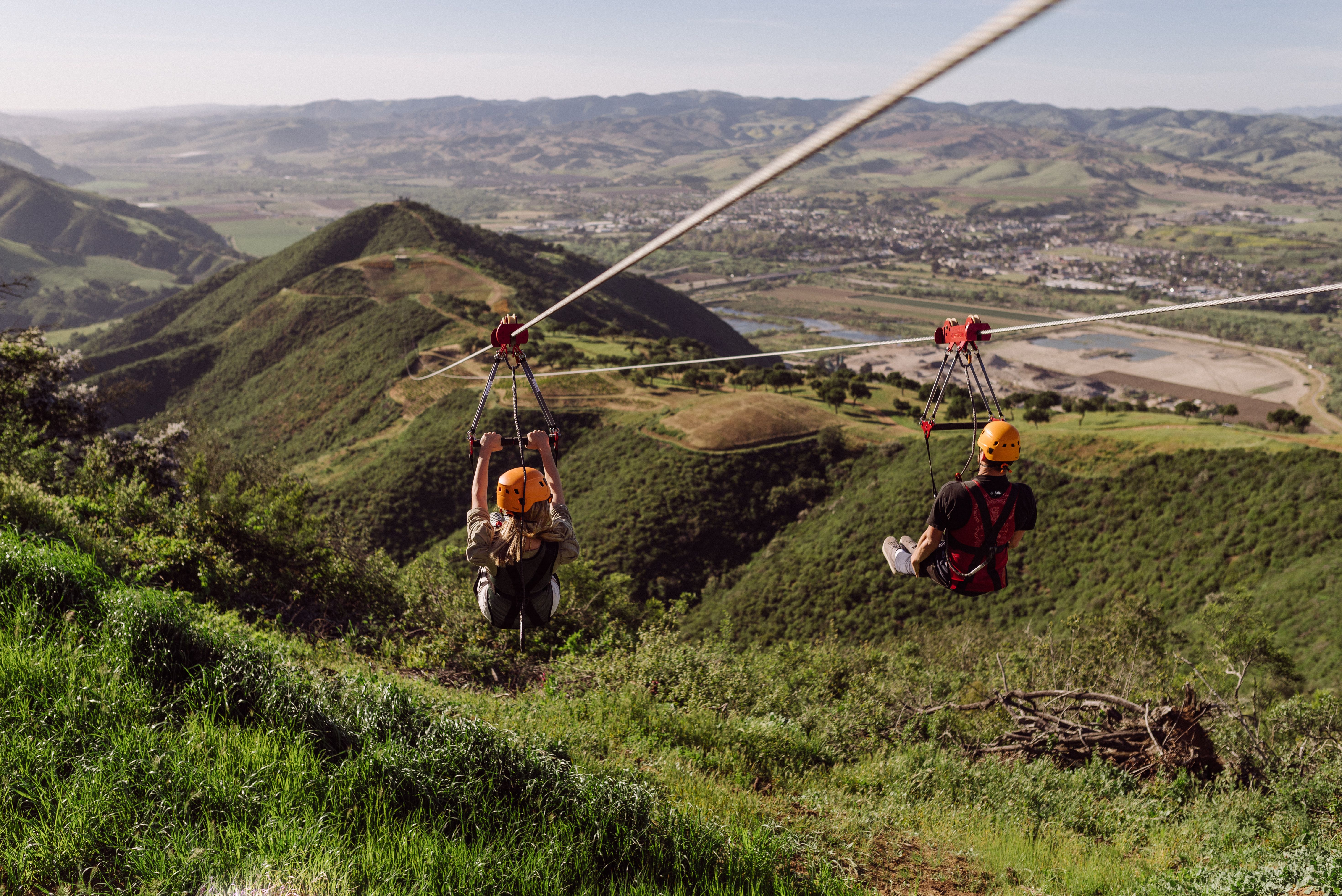 Orange-helmeted couple on ziplines above the Santa Ynez Valley